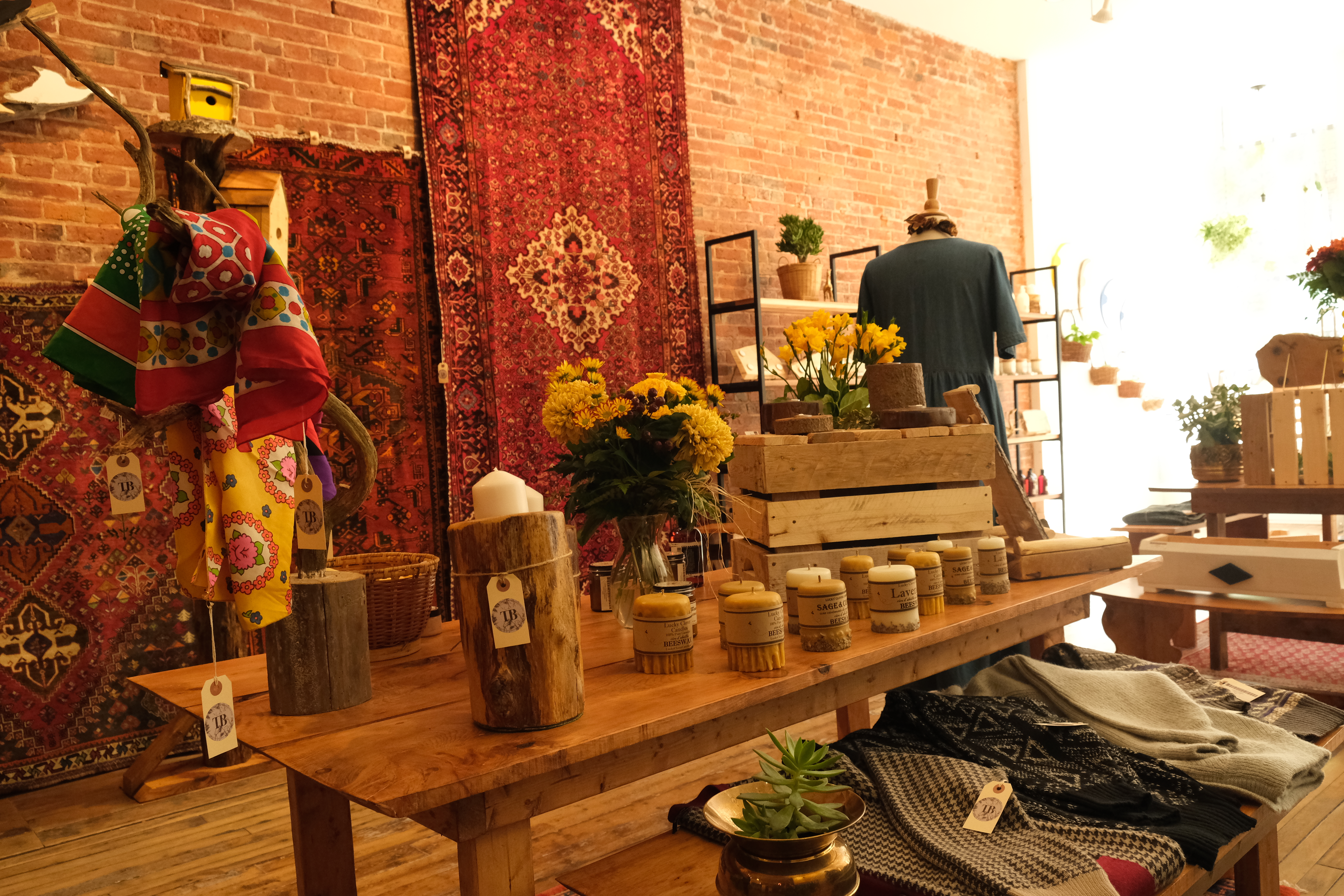Vintage store with table filled with vintage gift items including candles and plants.